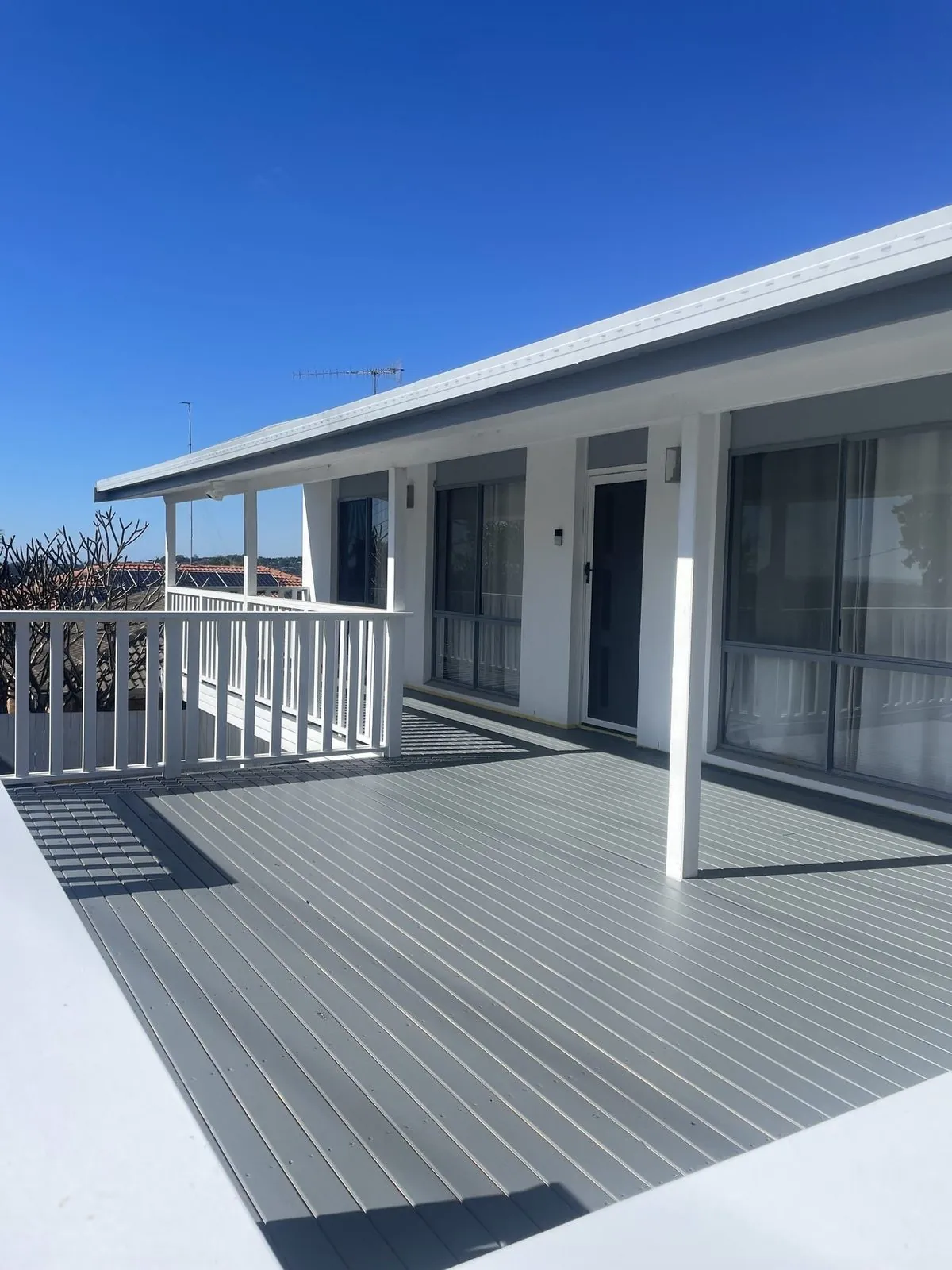 Exterior house repaint with fresh white walls and a timber deck on the Gold Coast