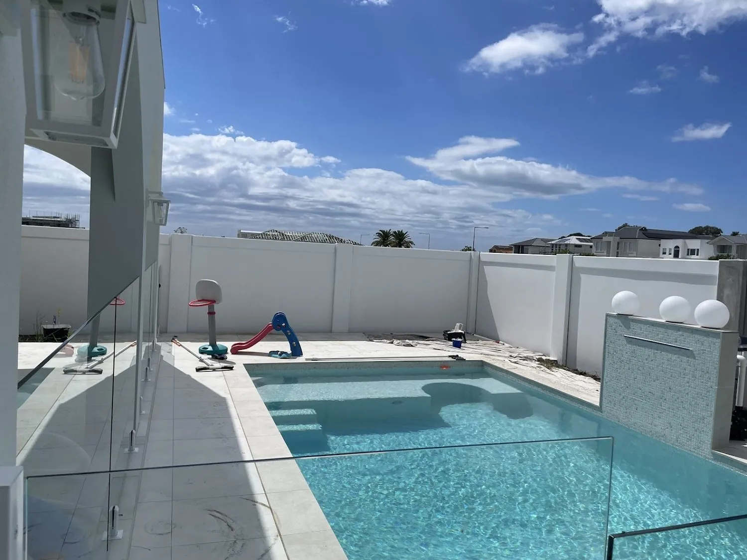 Freshly painted white render boundary wall around a pool