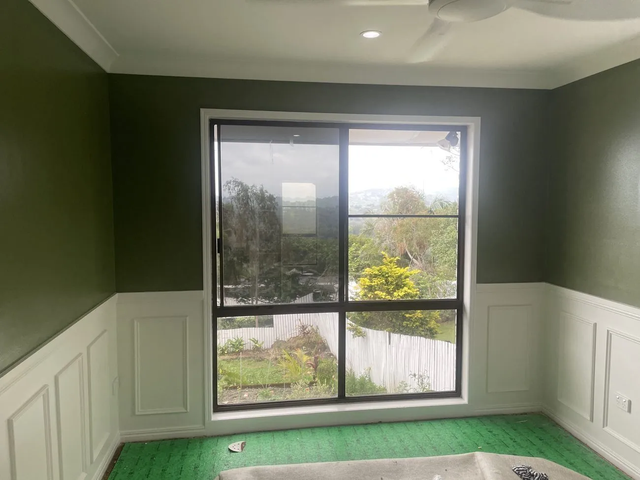 Green feature wall with white wainscoting and rural views